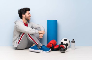 Yanal pozisyonda yerde oturan spor adam