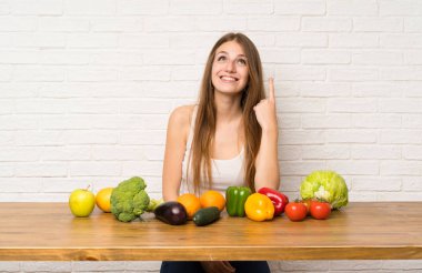 İşaret parmağıyla işaret eden bir sürü sebzeli genç kadın harika bir fikir.