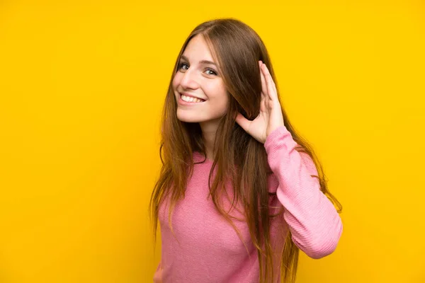 Sarı Duvarın Üzerinde Uzun Saçlı Genç Bir Kadın Elini Kulağına — Stok fotoğraf