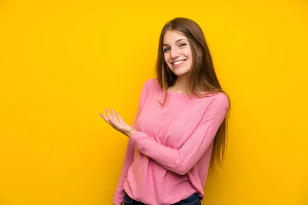 一个年轻的女人 一头长长的头发穿过孤立的黄墙 面带微笑地看着 — 图库照片