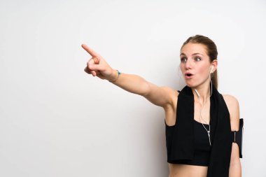 Young sport woman over isolated white background pointing away