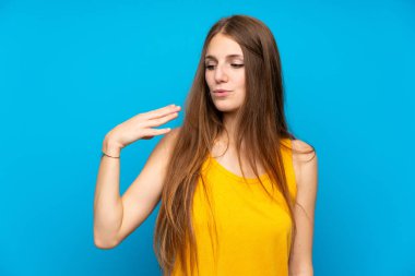 Yorgun ve hasta ifade ile izole mavi duvar üzerinde uzun saçlı genç kadın