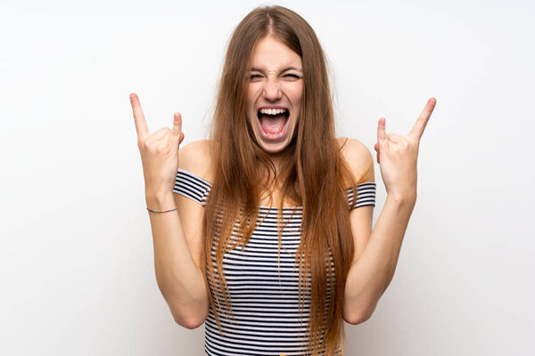 Young woman with long hair over isolated white wall making rock gesture