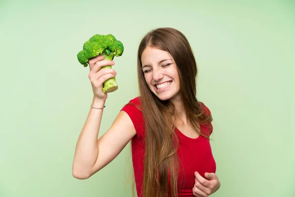 Mujer joven con el pelo largo sosteniendo un brócoli — Foto de Stock