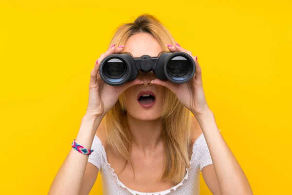 Jonge Blonde Vrouw Geïsoleerde Gele Muur Met Zwarte Verrekijker — Stockfoto