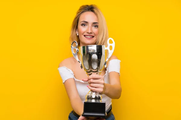 Young Blonde Woman Isolated Yellow Wall Holding Trophy — 스톡 사진