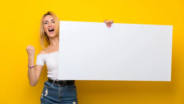 Jovem Loira Sobre Parede Amarela Isolada Segurando Cartaz Branco Vazio — Fotografia de Stock