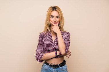 Pembe ceketli genç sarışın kadın izole edilmiş duvarın üstünde