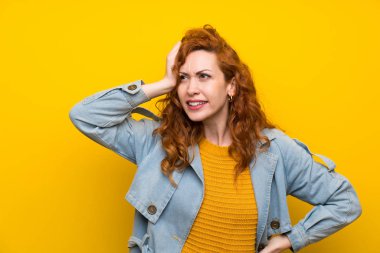 Redhead kadın izole sarı arka plan üzerinde şüpheler olan ve yüz ifadesi karıştırmayın