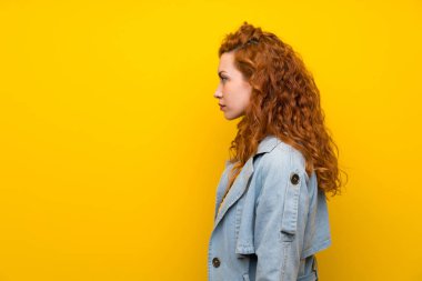 Izole sarı arka plan ayakta ve yan görünümlü üzerinde Redhead kadın