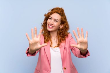 Izole mavi duvar üzerinde takım elbiseredhead kadın parmakları ile on sayma
