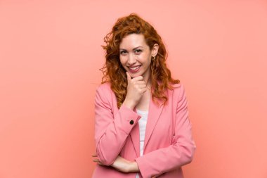 Izole pembe duvar gülerek üzerinde takım elbiseli Redhead kadın