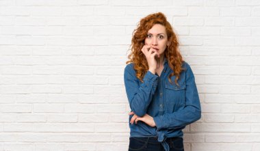 Sağ bakarken beyaz tuğla duvar üzerinde Redhead kadın şaşırttı ve şok