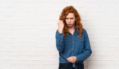 Kızgın jest ile beyaz tuğla duvar üzerinde Redhead kadın
