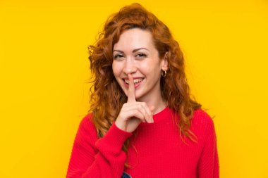 İzole sarı duvar üzerinde tulum ile Redhead kadın sessizlik jest yapıyor