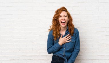 Beyaz tuğla duvar üzerinde Redhead kadın çok gülümsüyor