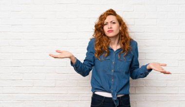 Beyaz tuğla duvar üzerinde Redhead kadın bir şey anlamak için mutsuz