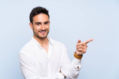 Izole mavi arka plan yan parmak işaret üzerinde Yakışıklı genç adam