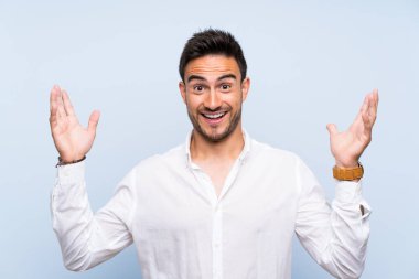 Yakışıklı genç adam üzerinde izole mavi arka plan çok gülümseyen