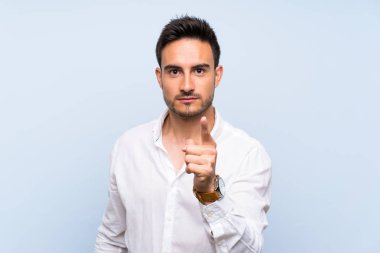 Izole mavi arka plan üzerinde Yakışıklı genç adam sinirli ve ön işaret