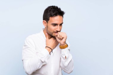 Izole mavi arka plan üzerinde Yakışıklı genç adam öksürük ve kötü duygu ile acı