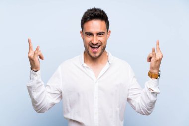 Izole mavi arka plan üzerinde rock jest yapma yakışıklı genç adam