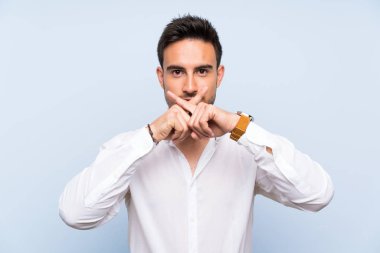 Izole mavi arka plan üzerinde sessizlik jest bir işaret gösteren yakışıklı genç adam