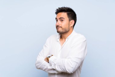 Izole mavi arka plan üzerinde Yakışıklı genç adam omuzları kaldırırken şüphe jest yapma