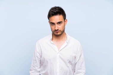 Üzgün ve depresif ifade ile izole mavi arka plan üzerinde Yakışıklı genç adam