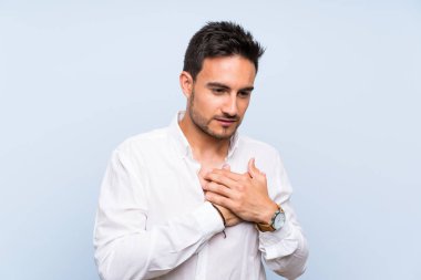 Izole mavi arka plan üzerinde yakışıklı genç adam kalbinde bir ağrı olan