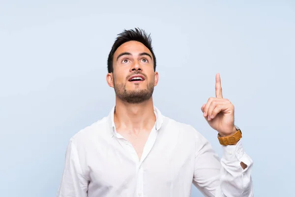 Guapo Joven Sobre Aislado Fondo Azul Apuntando Hacia Arriba Sorprendido — Foto de Stock