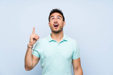 Izole arka plan üzerinde Yakışıklı genç adam işaret ve şaşırttı