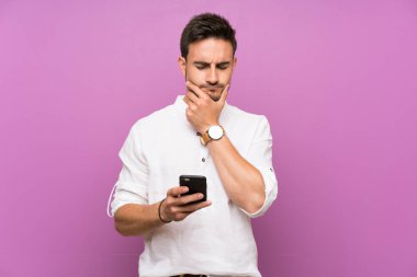 İzole arka plan üzerinde yakışıklı genç adam düşünme ve bir mesaj gönderme