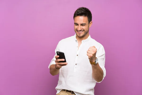 Joven Guapo Sobre Fondo Aislado Con Teléfono Posición Victoria —  Fotos de Stock