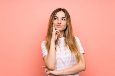 Izole pembe duvar üzerinde genç kadın bir fikir düşünme