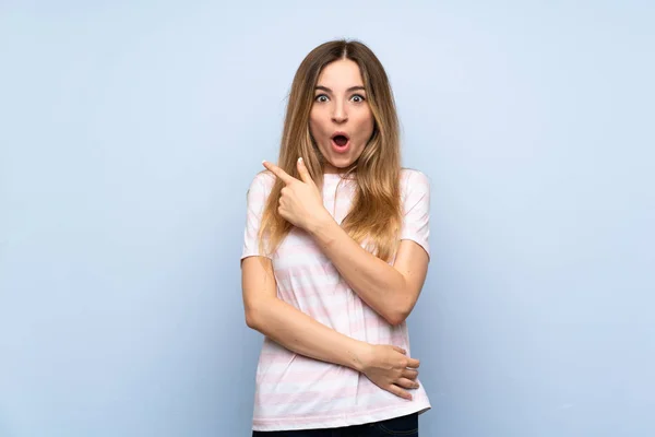 Jonge Vrouw Geïsoleerde Blauwe Achtergrond Verrast Wijzen Kant — Stockfoto