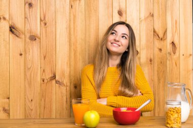 Mutfakta kahvaltı yapan genç bir kadın gülümserken yukarı bakıyor.