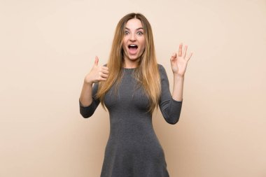 İzole edilmiş arka planda genç bir kadın tamam işareti ve işaret işareti gösteriyor.