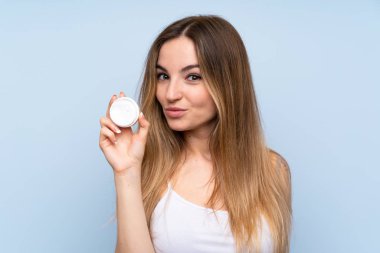 Nemlendirici ile izole mavi arka plan üzerinde genç kadın