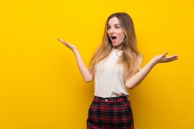 Sürpriz yüz ifadesi ile izole sarı duvar üzerinde genç kadın