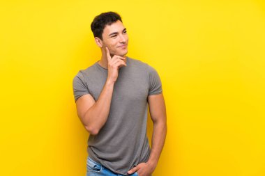 Izole sarı duvar üzerinde Yakışıklı adam bakarken bir fikir düşünme