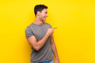 Izole sarı duvar üzerinde yakışıklı adam yan parmak işaret