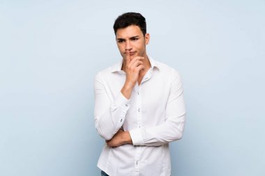 Mavi duvar üzerinde Yakışıklı adam şaşırttı ve doğru bakarken şok