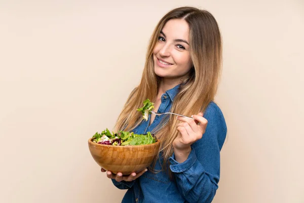 Молодая женщина с салатом на изолированном фоне — стоковое фото
