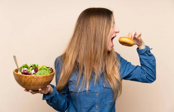 Mujer joven con ensalada sobre fondo aislado y sosteniendo un do —  Fotos de Stock