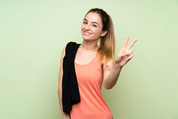 Yeşil Duvarın Üzerinde Gülümseyen Zafer Işareti Gösteren Genç Bir Kadın — Stok fotoğraf