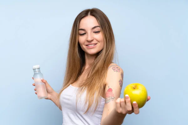 Ung kvinna över isolerad blå bakgrund med ett äpple och en bo — Stockfoto