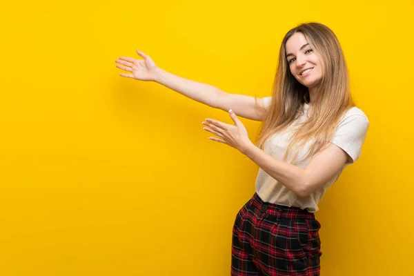 Mujer Joven Sobre Pared Amarilla Aislada Extendiendo Las Manos Lado —  Fotos de Stock