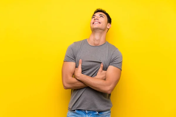 Knappe Man Geïsoleerde Gele Muur Omhoog Kijken Terwijl Glimlachend — Stockfoto