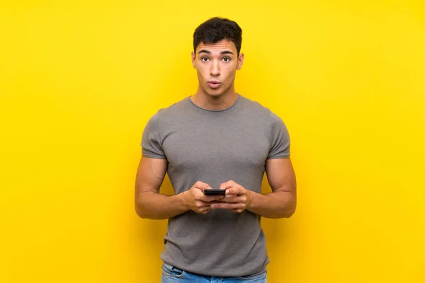 Hombre Guapo Sobre Aislada Pared Amarilla Sorprendido Enviando Mensaje —  Fotos de Stock